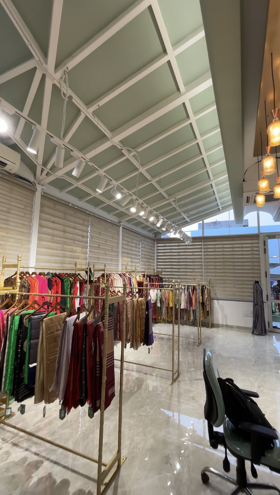 Clothing displayed on golden rails beneath the boutique’s pale green vaulted ceiling