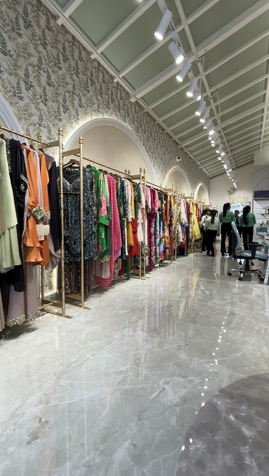 Long view through Kalii boutique with colourful apparel rails, arched mirrors and patterned walls