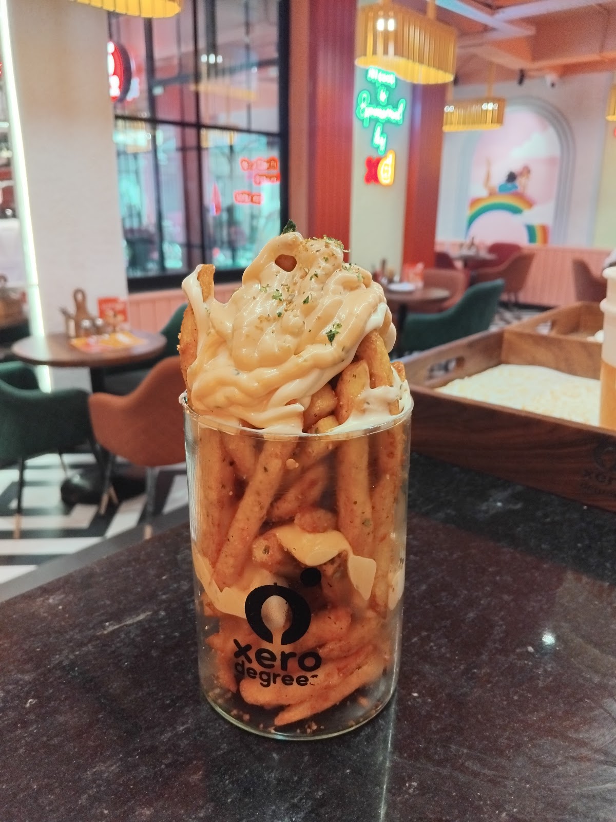 Loaded fries in a Xero Degrees glass with the colourful Jabalpur café seating behind